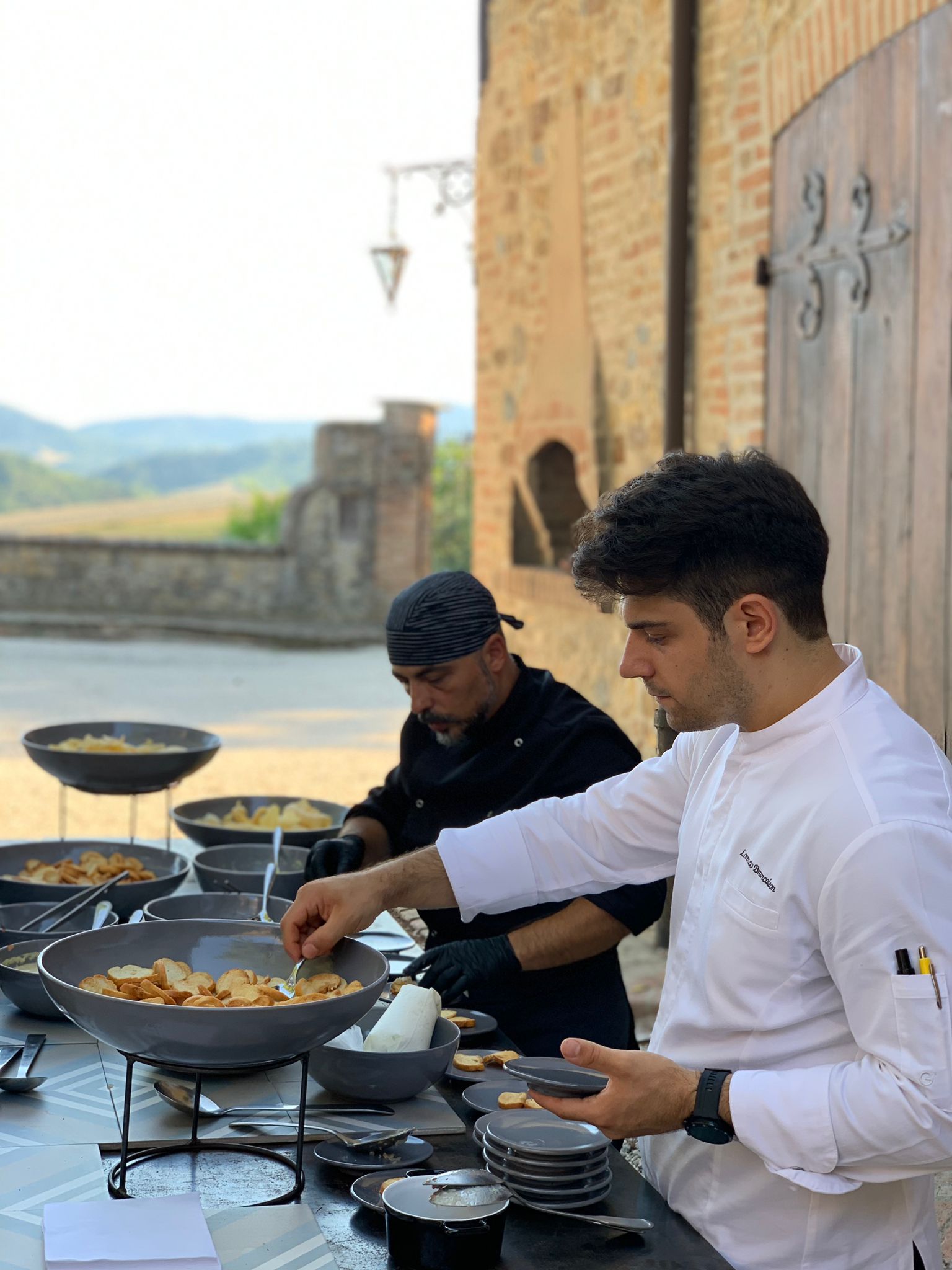 Lorenzo serving outdoors in front of a brick building