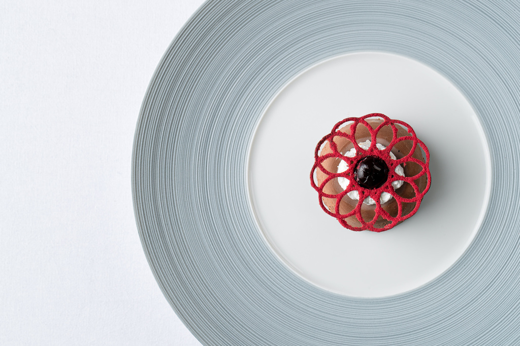 A red dessert on a plate with a circular texture